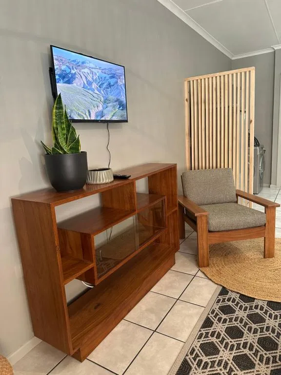 Living room with TV mounted above wooden entertainment unit and comfortable armchair