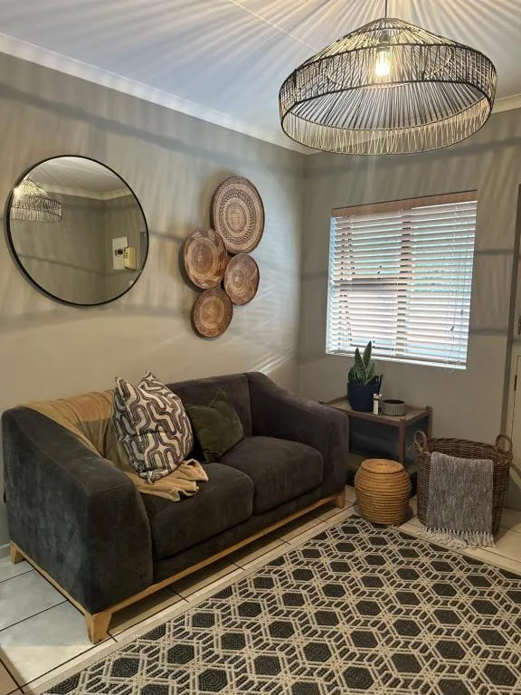 Modern lounge with dark sofa, woven pendant light, and decorative wall art