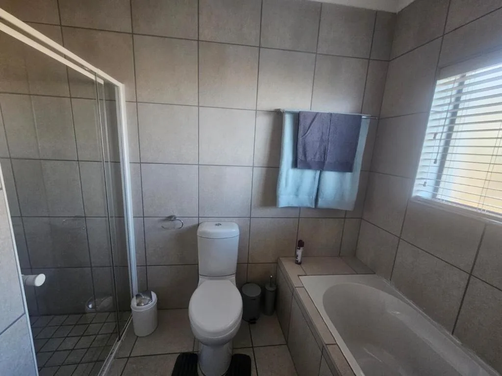 Modern bathroom with shower enclosure, toilet, and bathtub with tiled walls