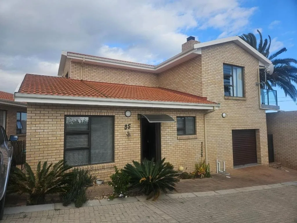 Modern brick house with red tile roof and palm trees in front