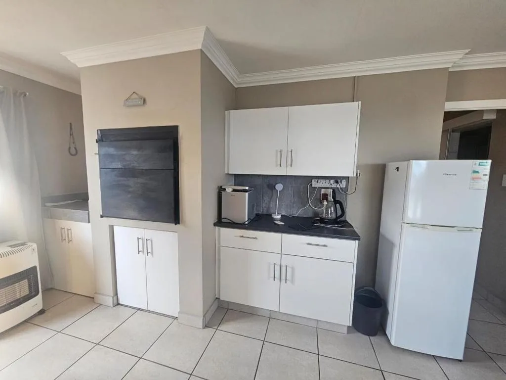Modern kitchen with white cabinetry, black countertop, and white refrigerator