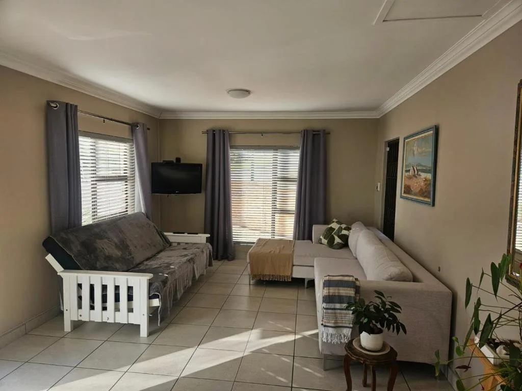 Spacious lounge with comfortable seating, wall-mounted TV, and bright natural light from windows