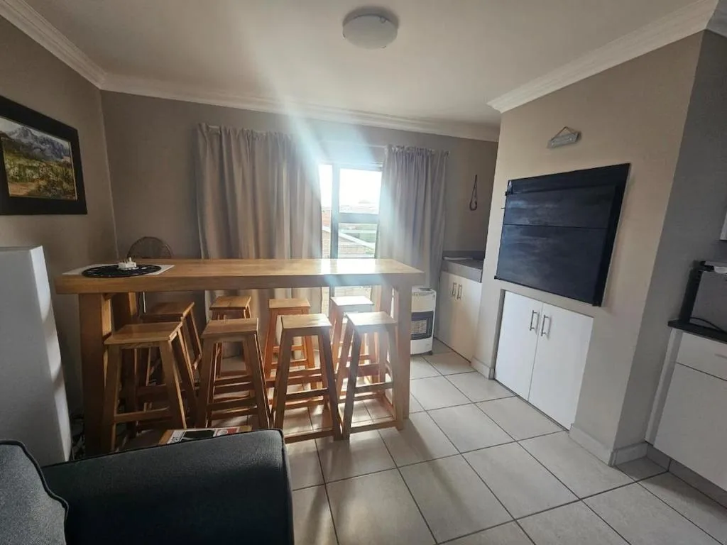 Open-plan living area with dining counter, sofa, TV, and scenic window views