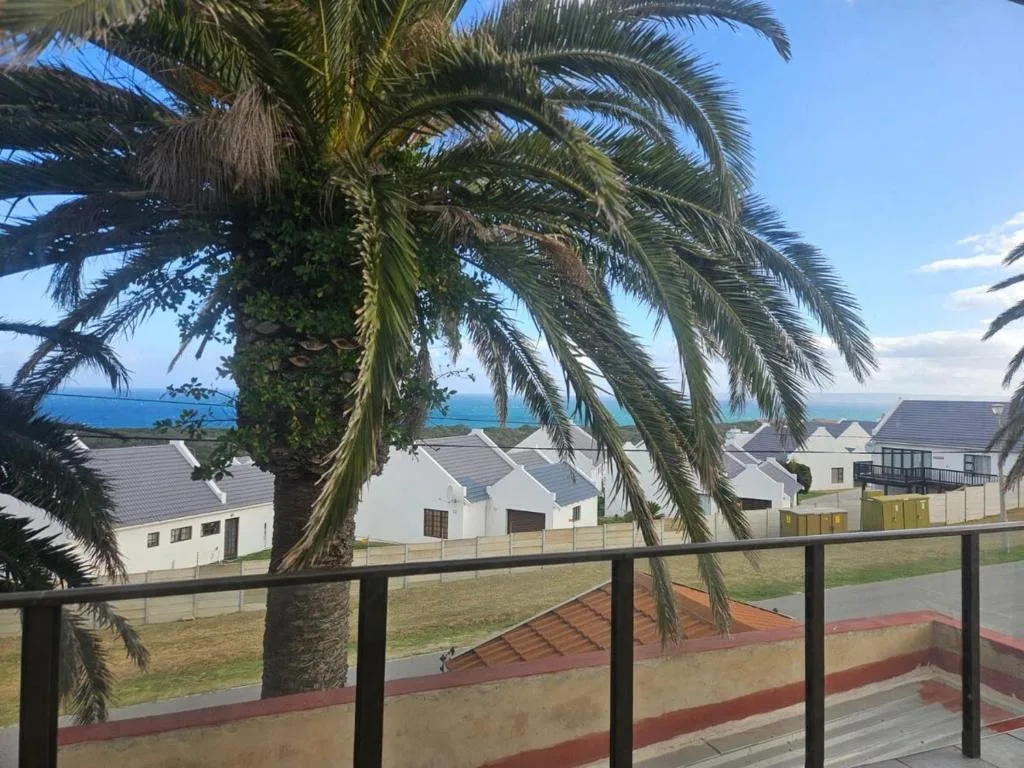 Ocean view framed by palm tree and coastal village architecture below