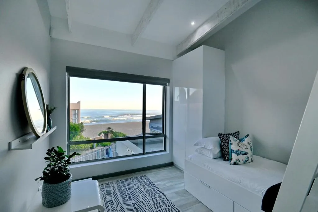 Bright bedroom with ocean view through large sliding windows and built-in bed