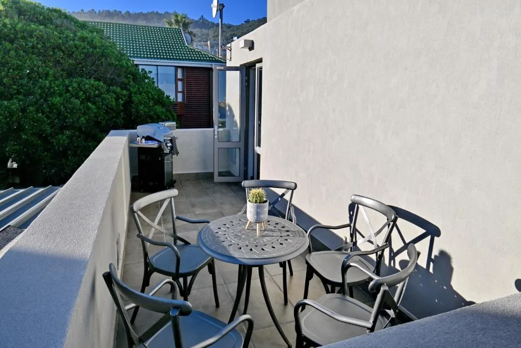 Outdoor patio with metal table, chairs, and mountain views beyond
