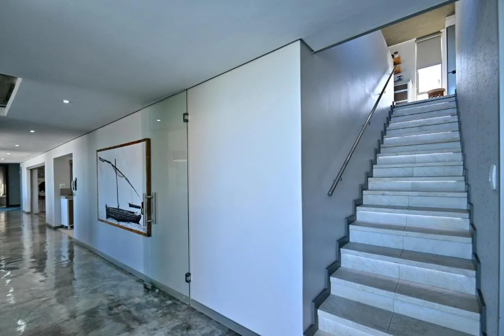 Modern interior staircase with tile steps and metal handrail leading upward