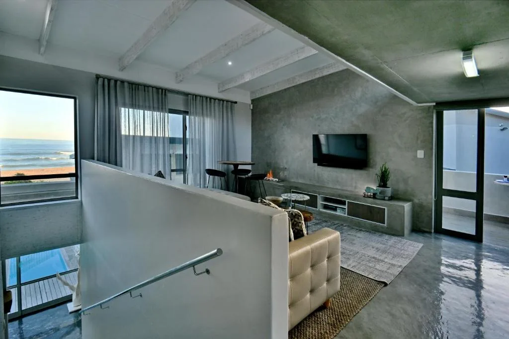 Modern lounge with ocean view, TV, and contemporary furniture overlooking the sea