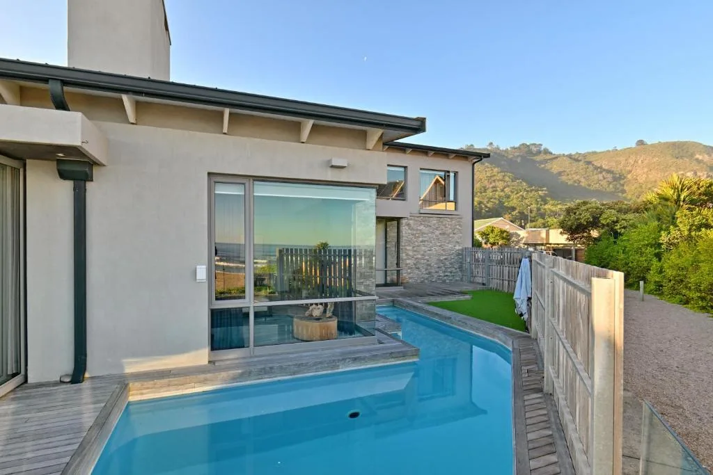 Modern swimming pool with deck overlooking lush green mountains and valley views