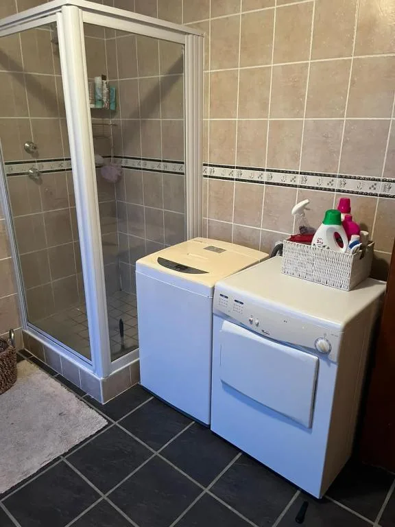 Modern bathroom with enclosed shower, washing machine and dryer units
