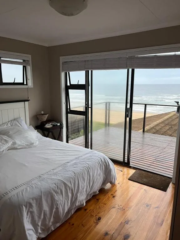Bedroom with ocean view through glass doors and deck access