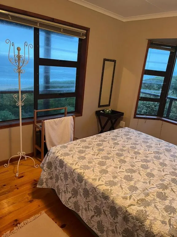 Bedroom with double bed, wooden floors, and expansive windows overlooking countryside views