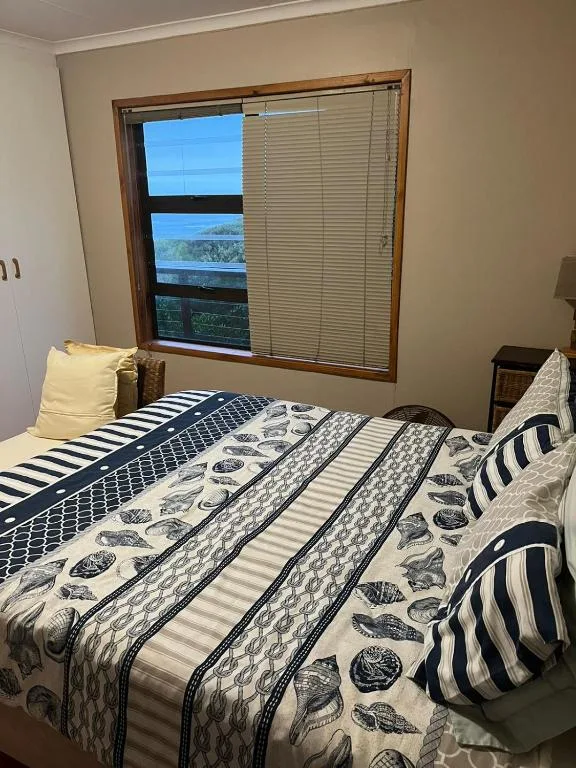 Bed with patterned navy and white bedding, window with garden view