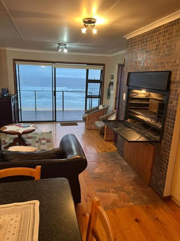Living room with fireplace, ocean views through glass doors, comfortable seating