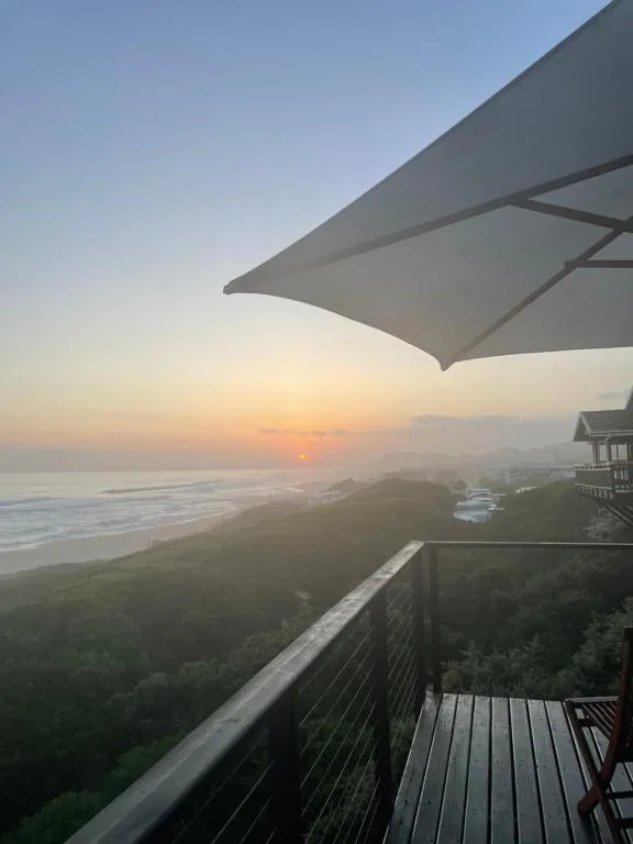 Sunrise over coastal landscape with beach, mountains, and ocean visible from deck