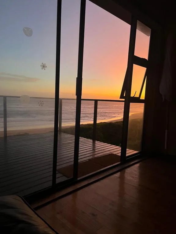 Stunning sunset over water viewed through large glass doors and deck