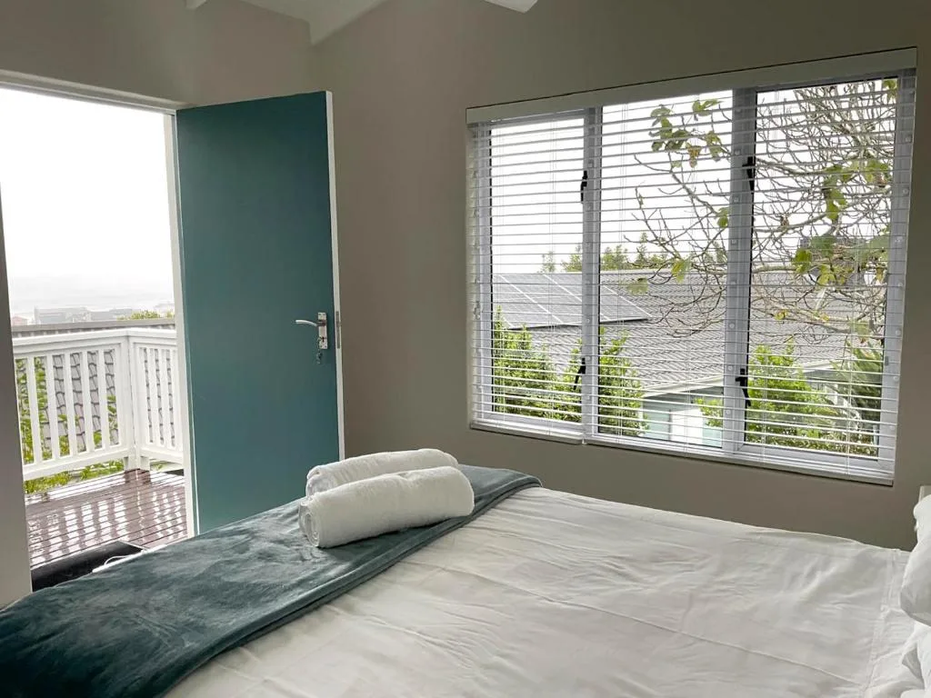 Bright bedroom with queen bed, teal accent door, and deck access doors