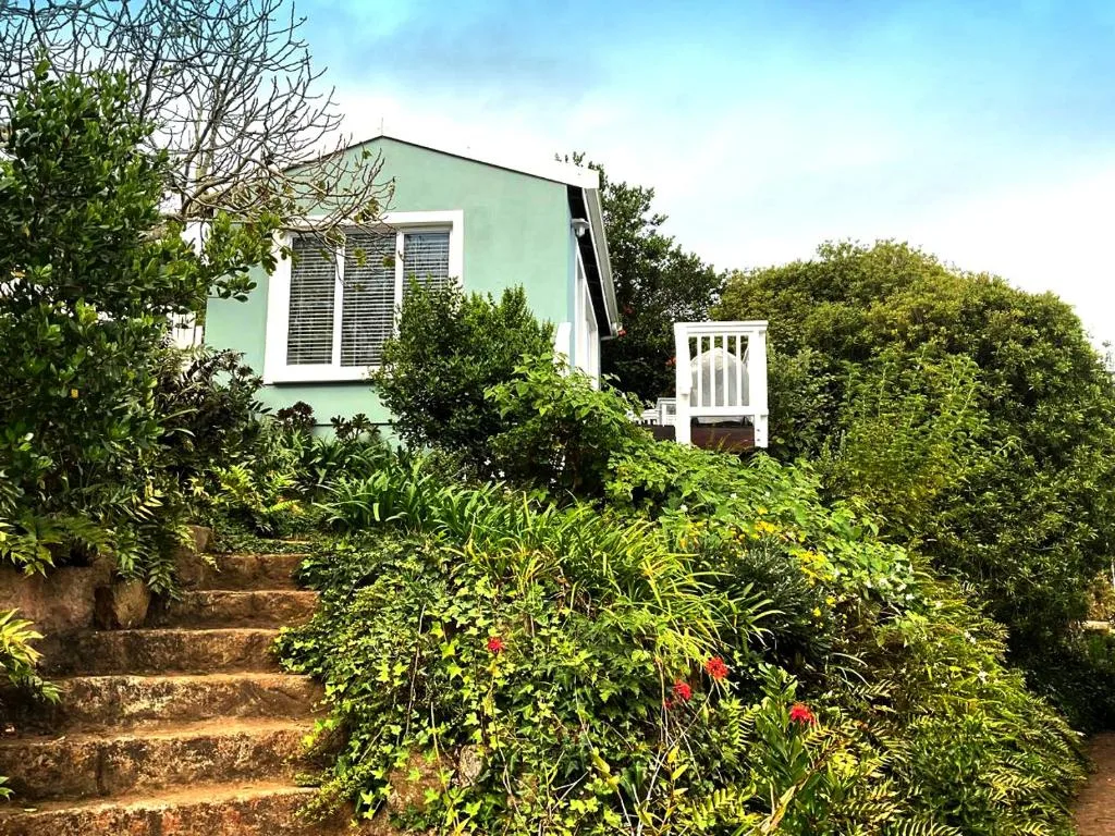 Pale green cottage with lush garden and stone steps leading to entrance