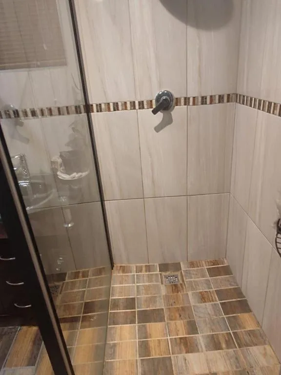 Spacious shower enclosure with glass door and neutral tile finishes