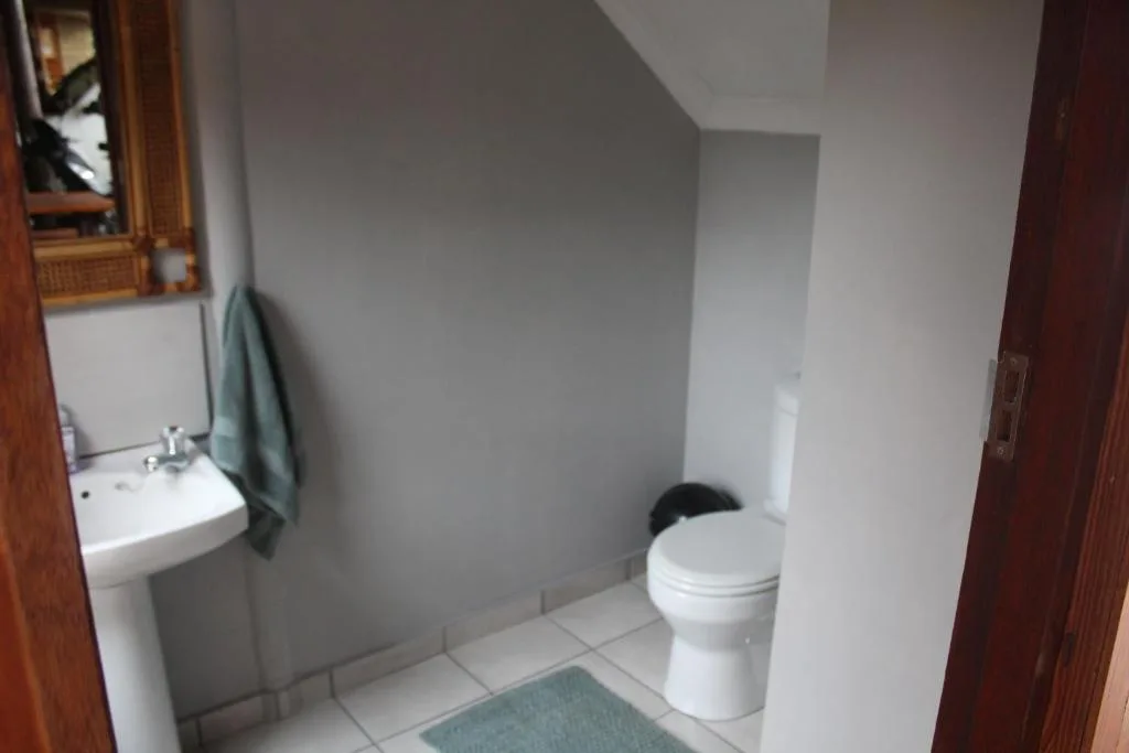 Clean bathroom with pedestal sink, toilet, and tiled floor