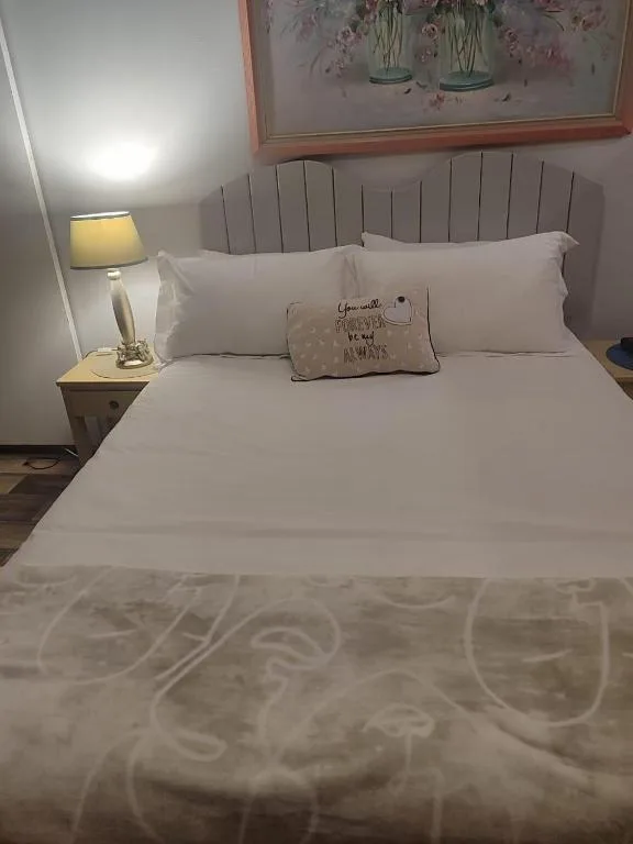 Comfortable bed with grey upholstered headboard and white bedding, bedside lamp