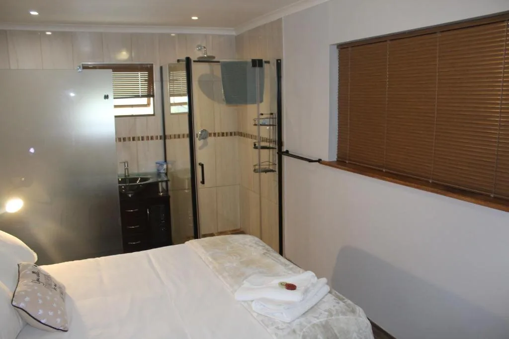 Bright bedroom with double bed and ensuite bathroom visible through open door