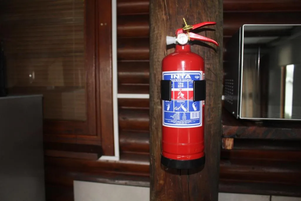 Red fire extinguisher mounted on wooden beam indoors