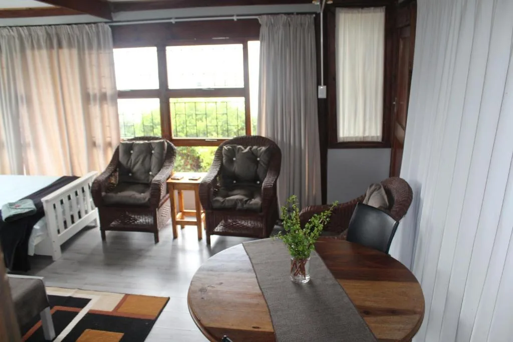 Spacious lounge with dark leather armchairs, wooden dining table, and garden views