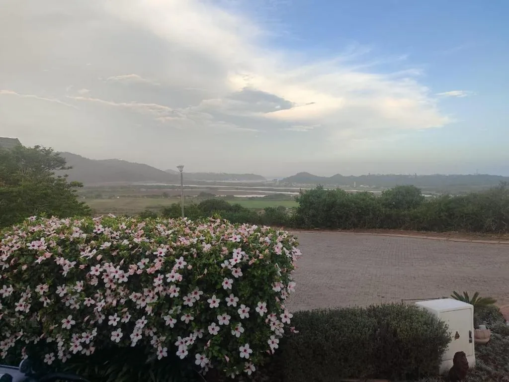 Scenic lagoon and mountain vista from property garden with flowering plants