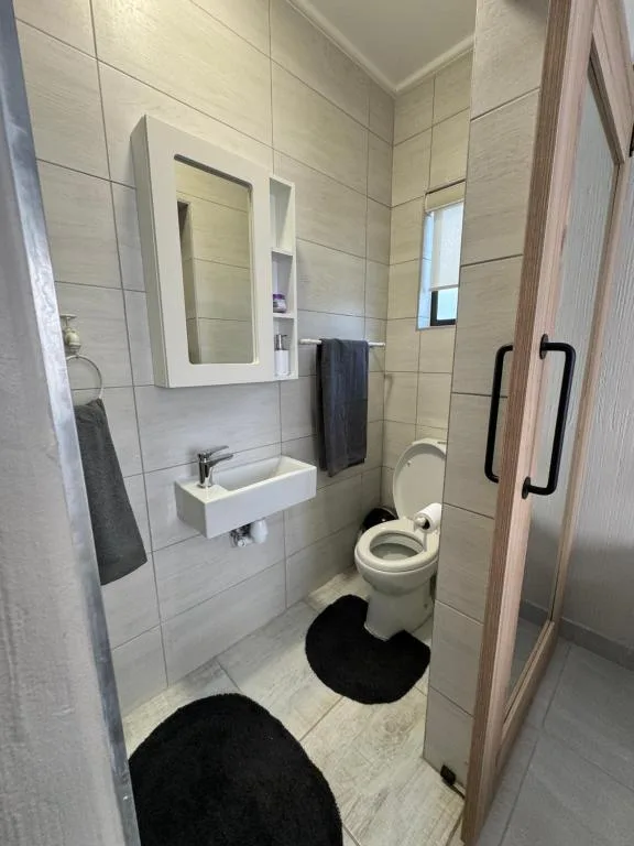 Modern bathroom with wall-mounted sink, toilet, and mirrored cabinet