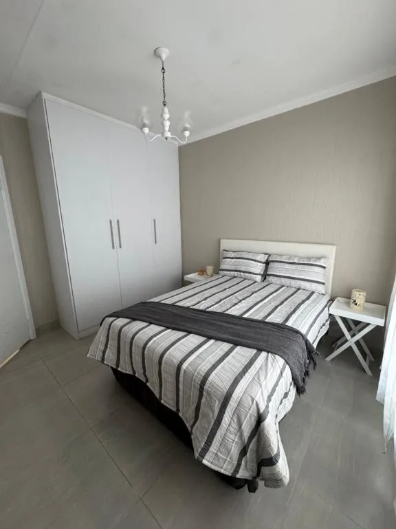 Bright bedroom with striped bedding, white wardrobe, and pendant light fixture