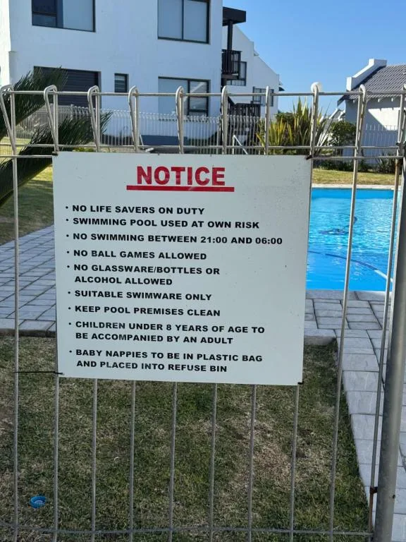 Pool safety notice sign with rules and regulations posted on fence