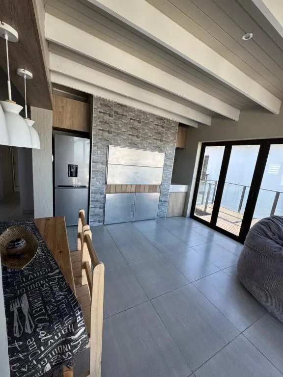 Modern open-plan lounge with kitchen, fireplace, and ocean views