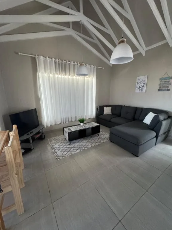Modern living room with black sectional sofa, TV, and pendant lighting