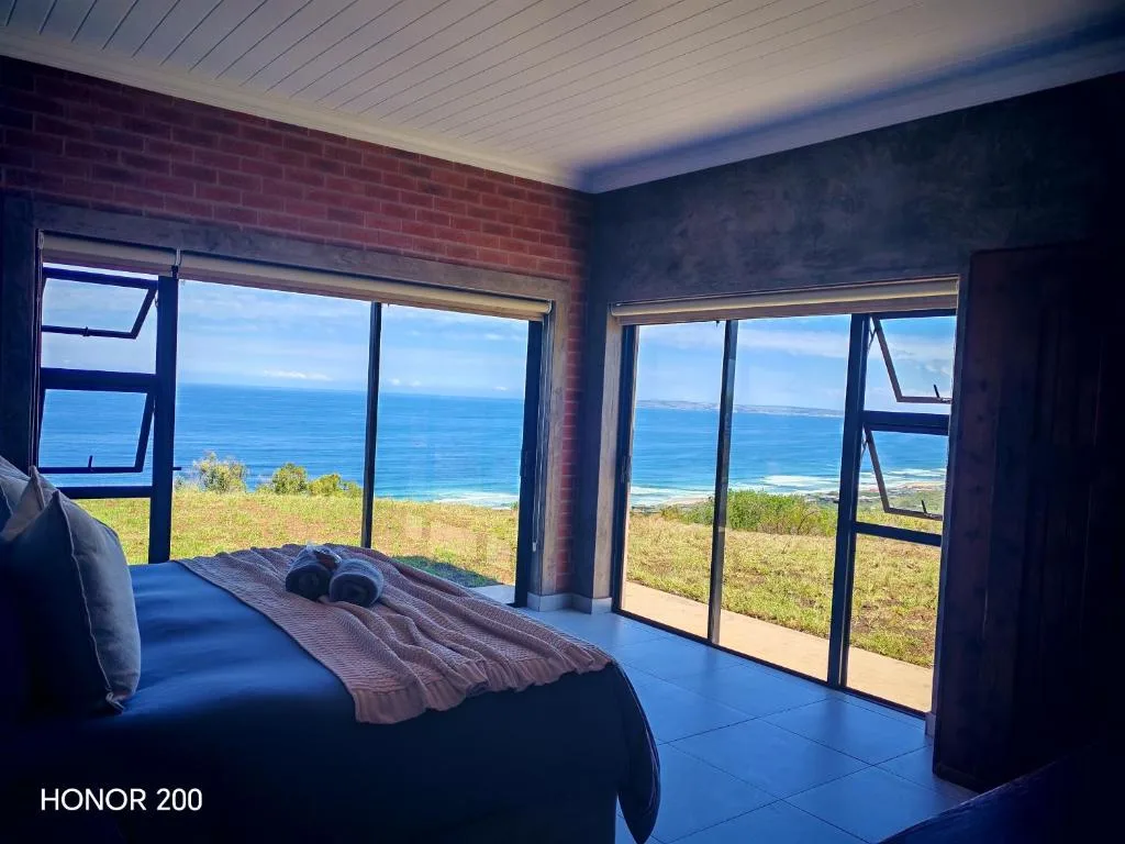 Bedroom with ocean view through large windows and glass doors