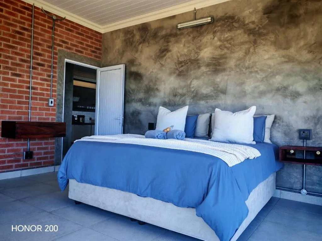 Modern bedroom with blue bedding, white pillows, industrial textured walls