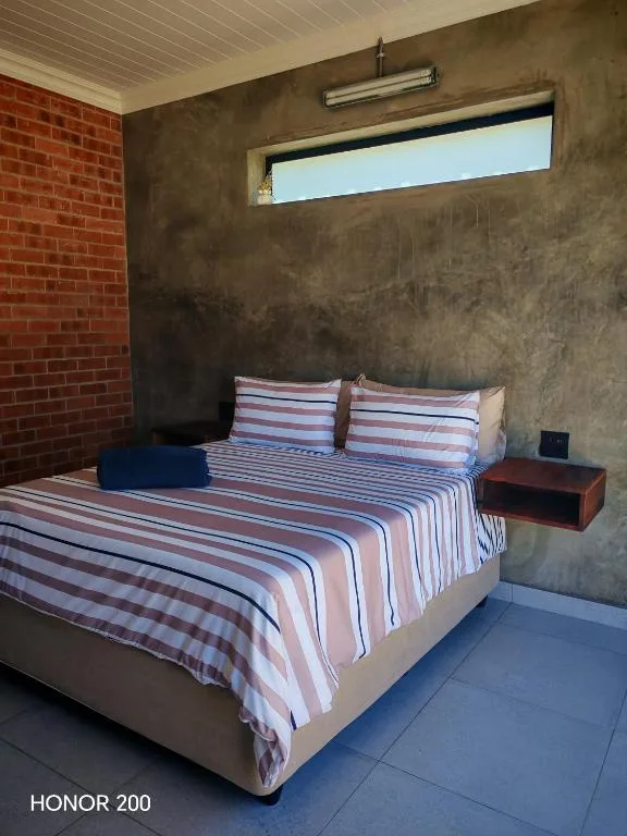 Modern bedroom with striped bedding, brick accent wall, and high window