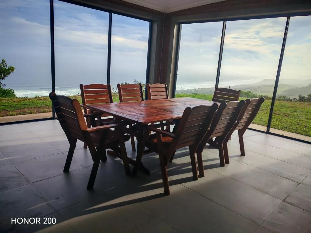 Dining table with chairs on covered deck overlooking mountains and sea