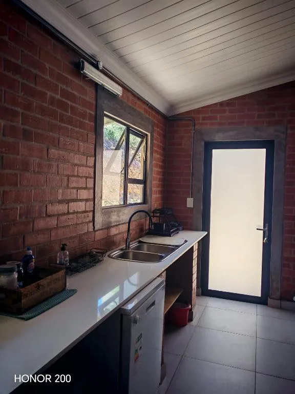 Compact kitchen with sink, counter space, and brick walls