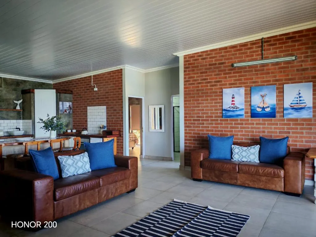 Open-plan lounge with brown leather sofas and blue cushions, nautical artwork