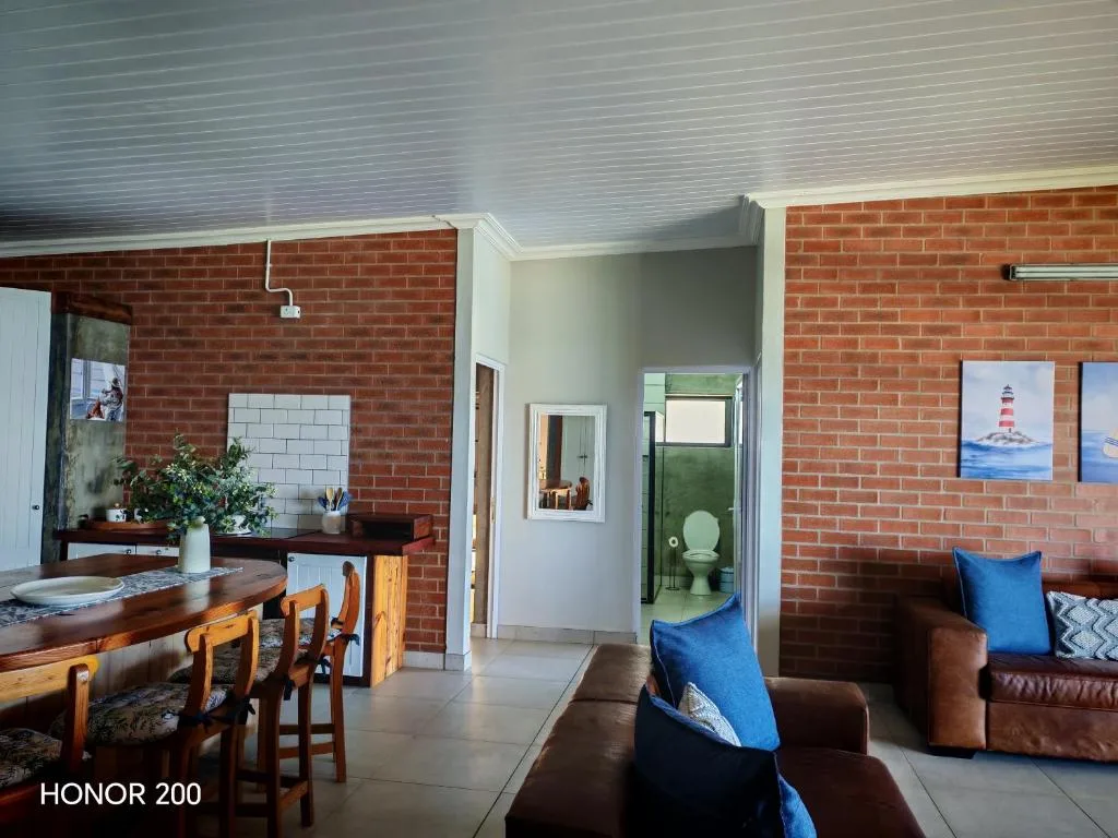 Open-plan lounge with brown leather sofas and blue cushions, brick walls