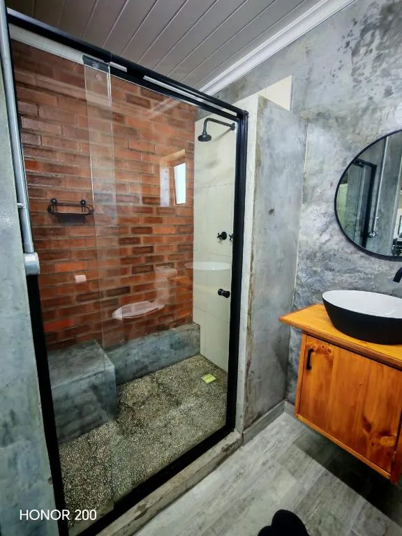 Modern bathroom with brick shower, vessel sink, and wooden vanity
