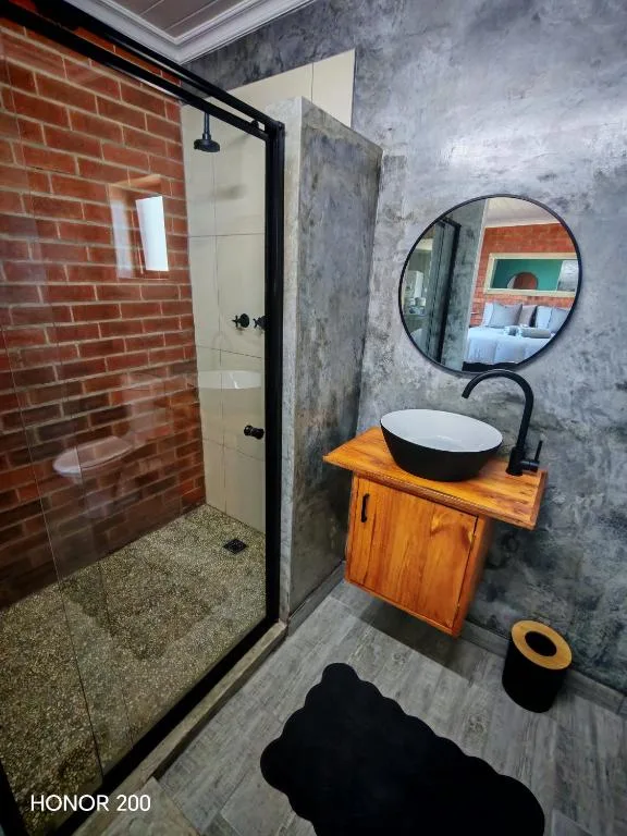 Modern bathroom with brick shower, wooden vanity, and round mirror