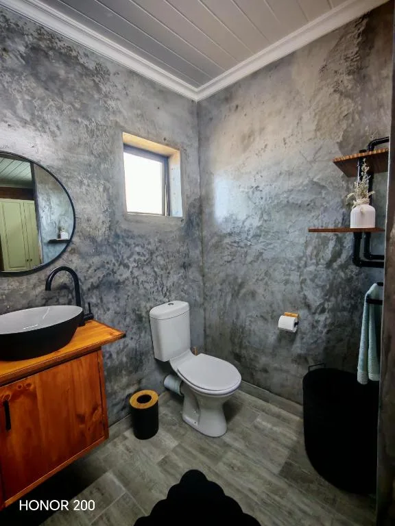 Modern bathroom with concrete walls, black vessel sink, and white toilet fixture