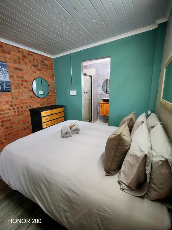 Bright bedroom with queen bed, turquoise walls, exposed brick feature