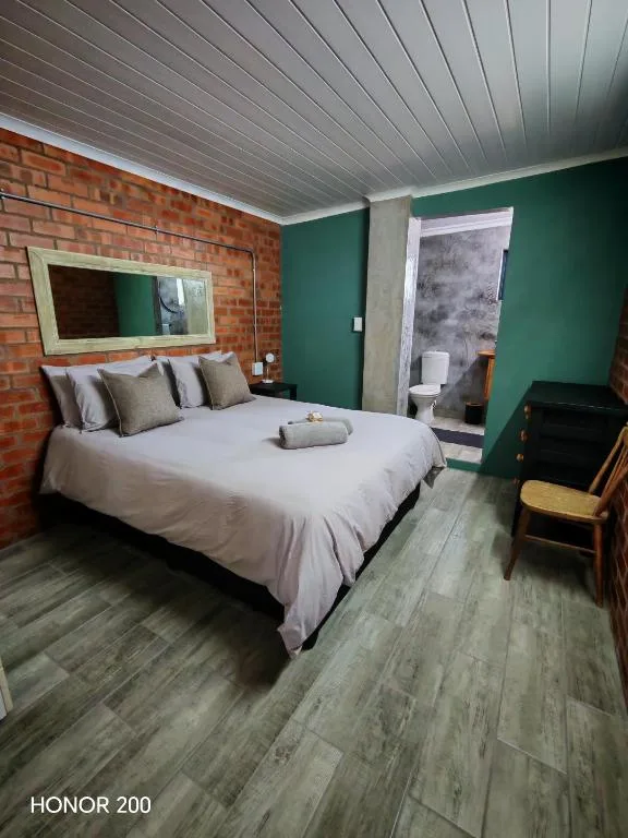 Spacious bedroom with queen bed, green accent wall, exposed brick