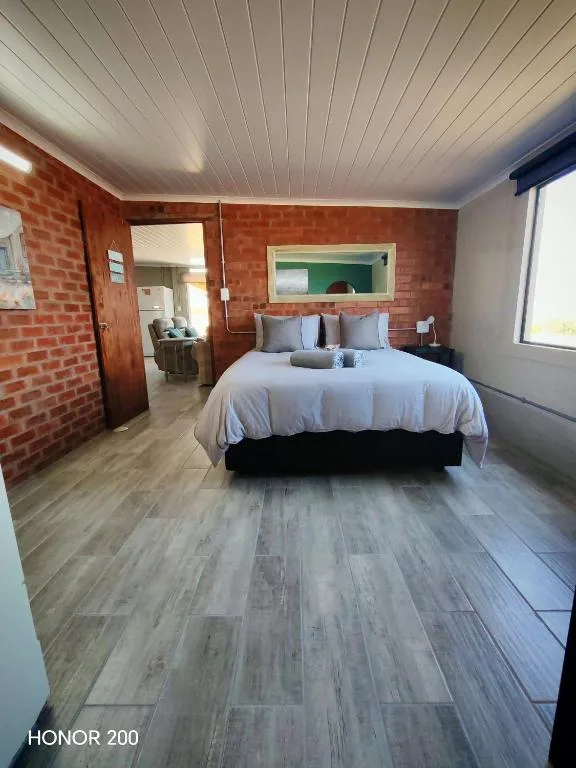 Spacious bedroom with queen bed, brick accent wall, white ceiling