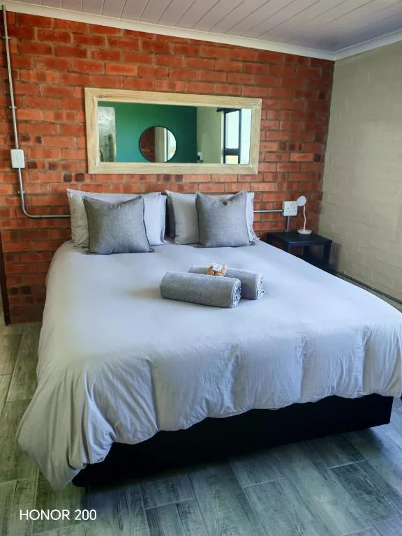 Modern bedroom with white bedding and blue pillows against exposed brick wall
