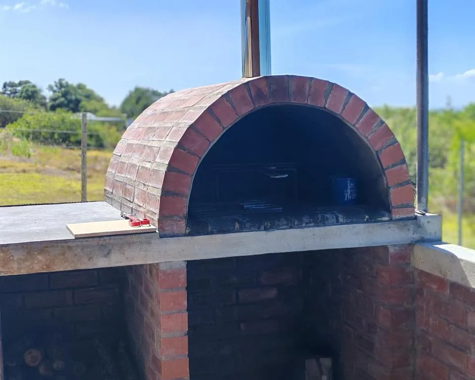 Traditional brick wood-fired pizza oven with countryside views beyond