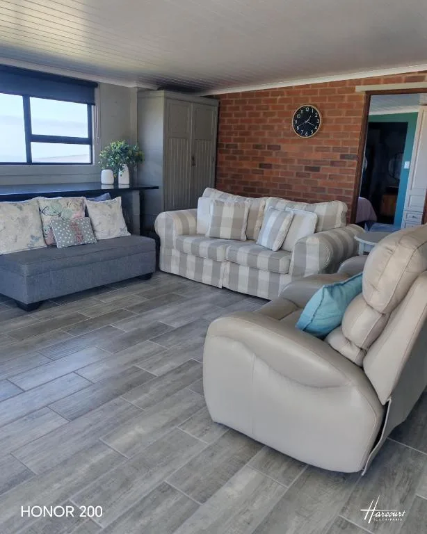 Spacious lounge with multiple sofas and natural light from windows
